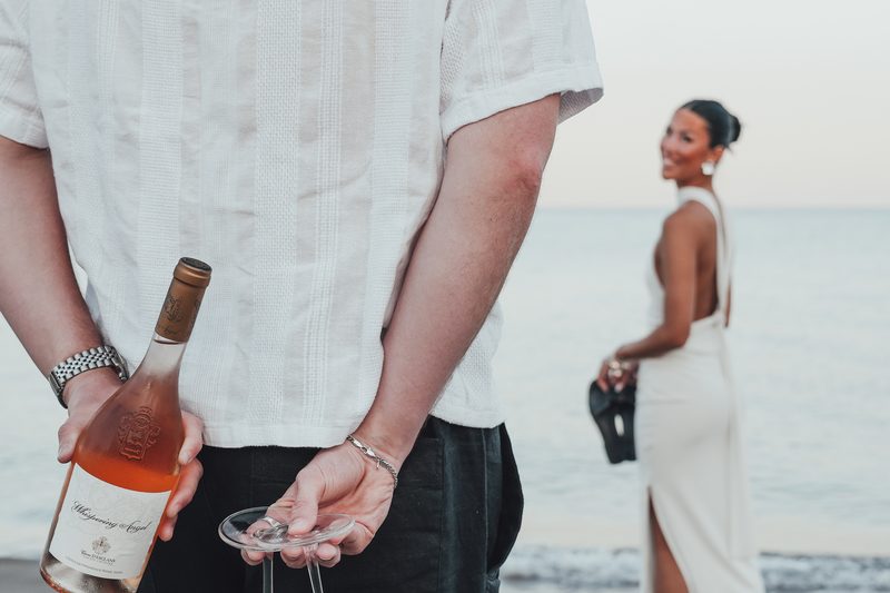 Couple walking on the beach in front of Starlight with drinks