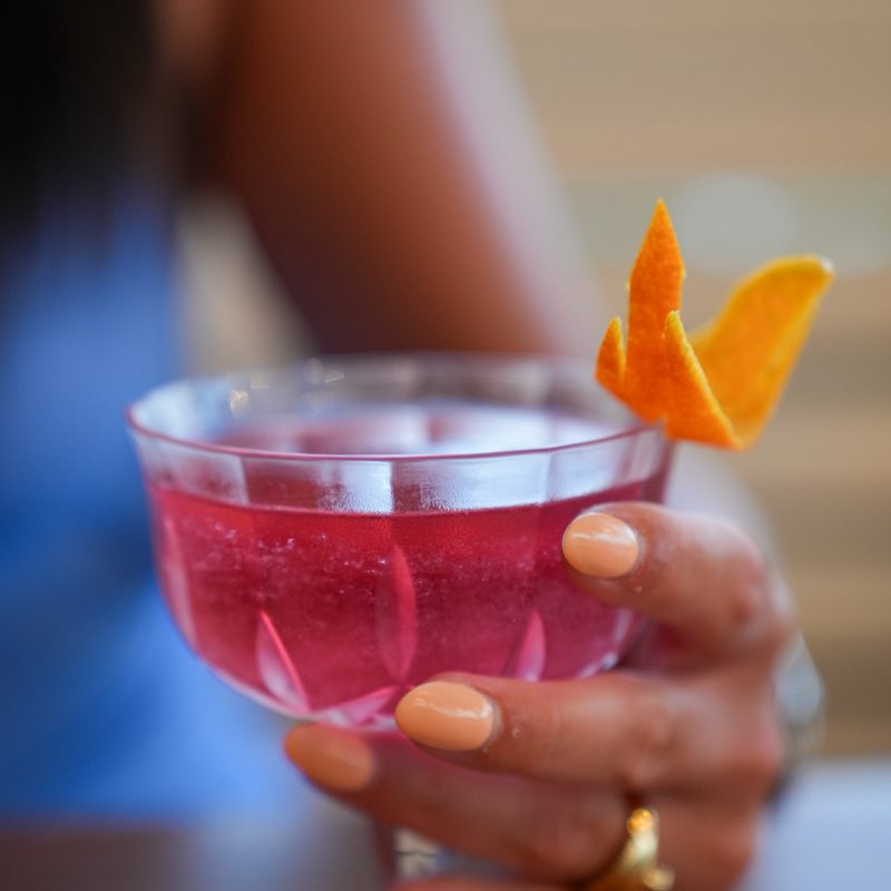 Pink signature cocktail held against the light at Starlight Beach Bar