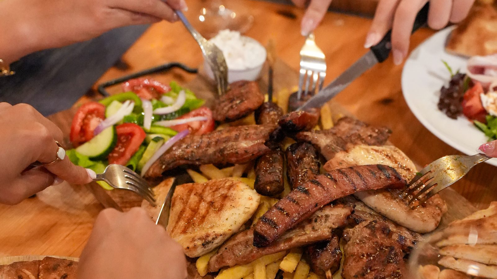 Sharing platters, grilled meats and cocktails spread across a table at Starlight Kitchen in the evening