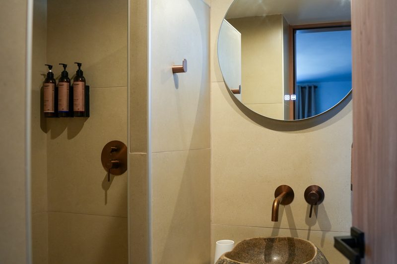 Penthouse bathroom with stone basin, round mirror and rainfall shower